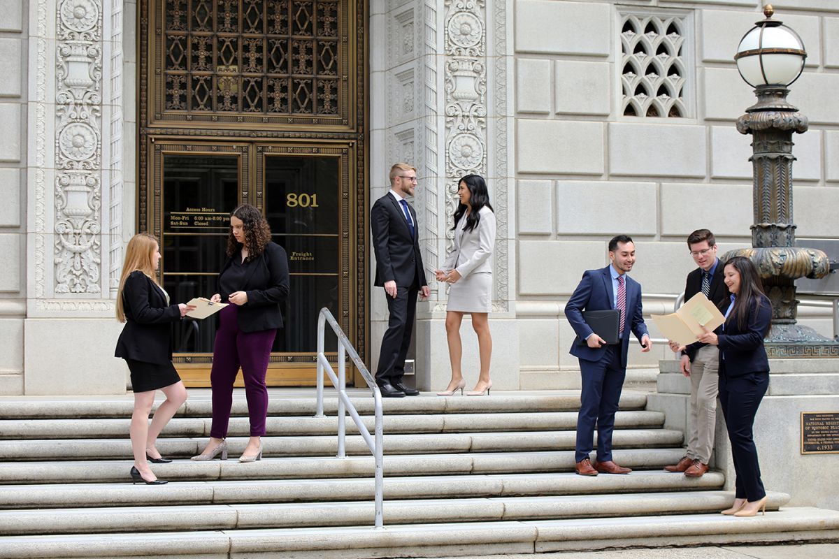 Seven students converse on the steps of a government building