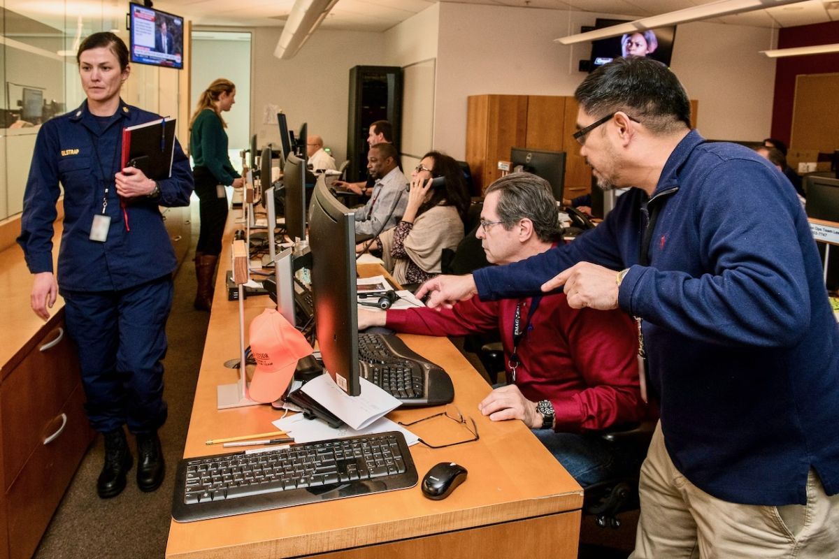 An emergency response team is shown working at their computer monitors.