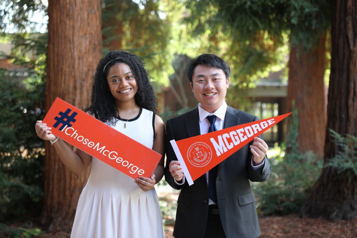 two students holding signs. left: I Choose McGeorge, right: McGeorge