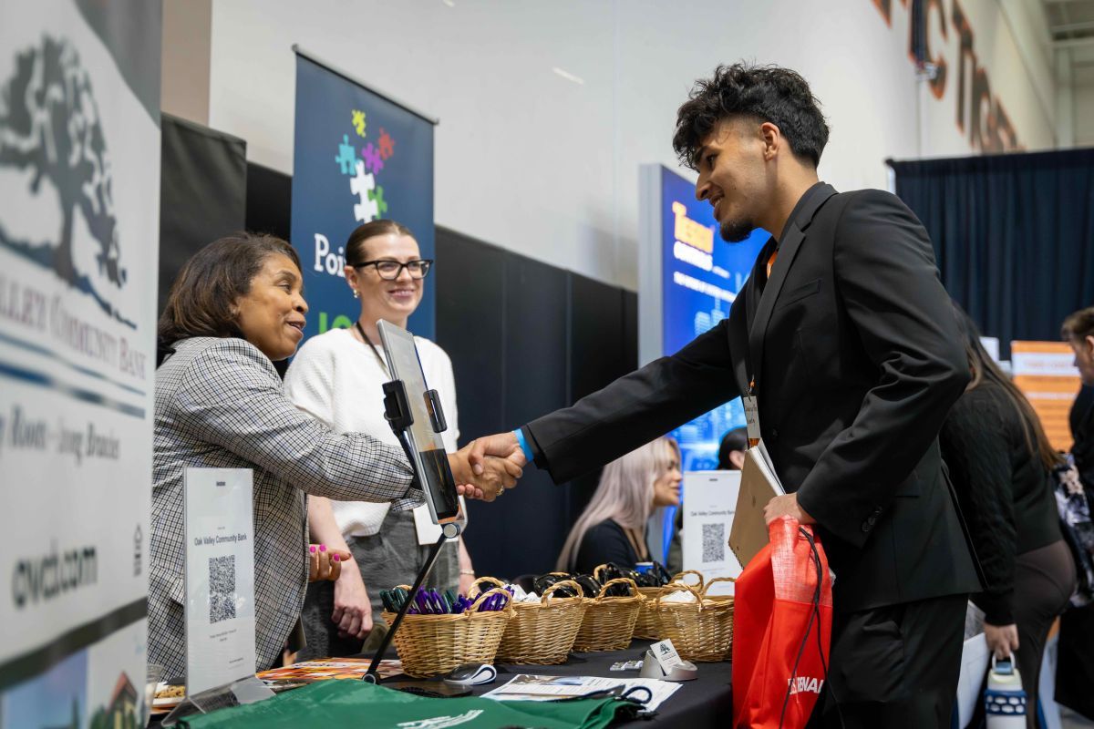 a student shakes the hand an an exhibit employer at a career fair