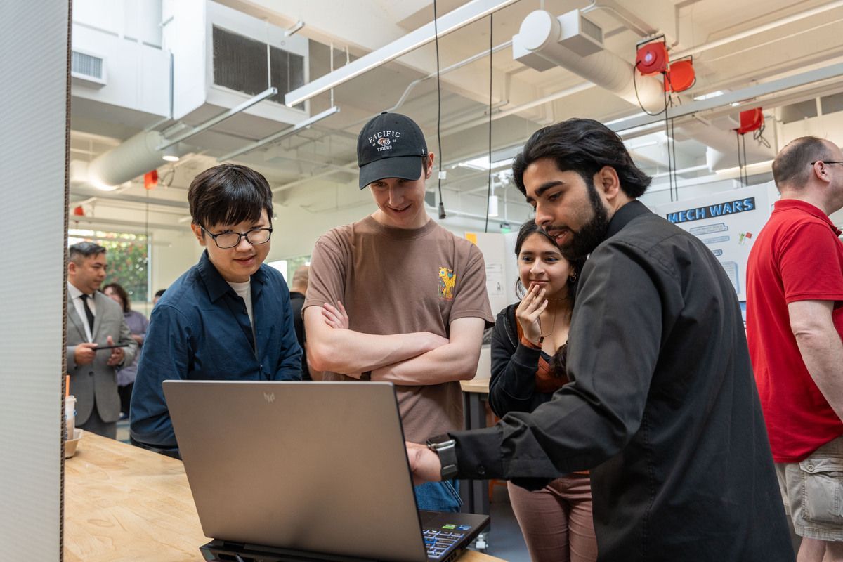 students look at a computer during senior project day