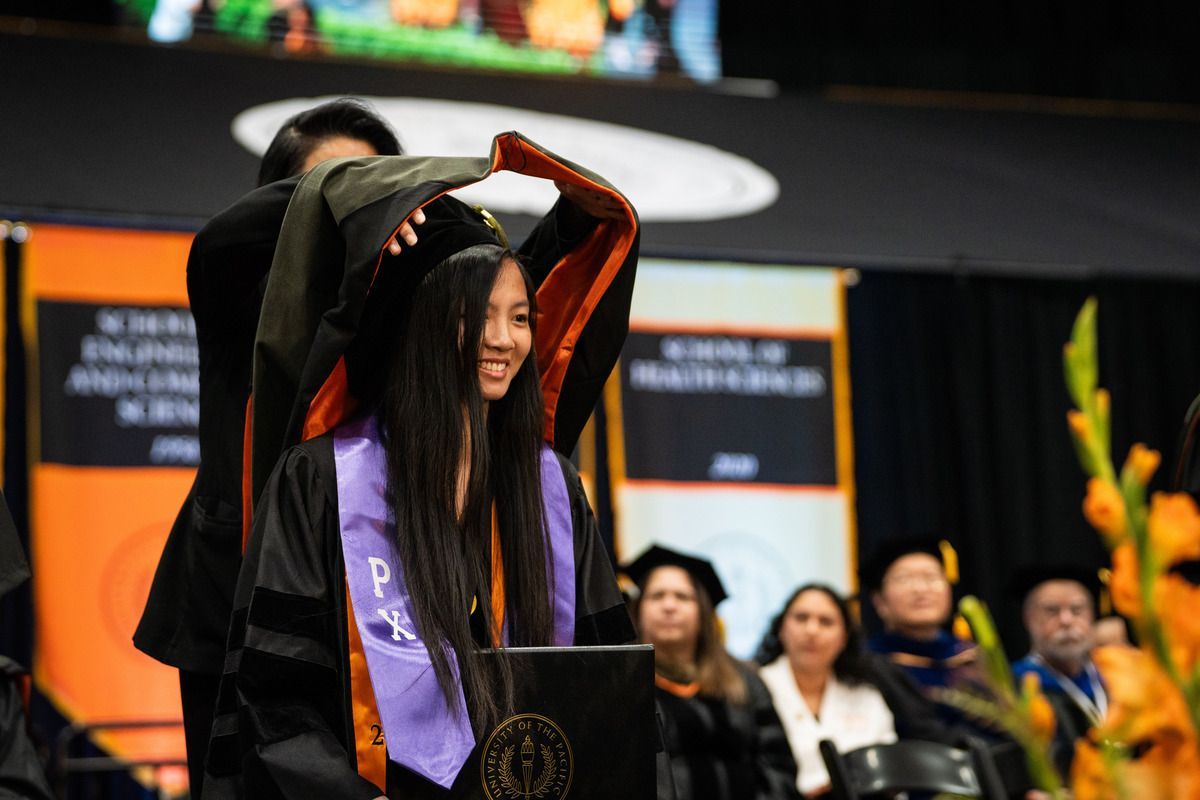 a pacific graduate receives her hood at commencement