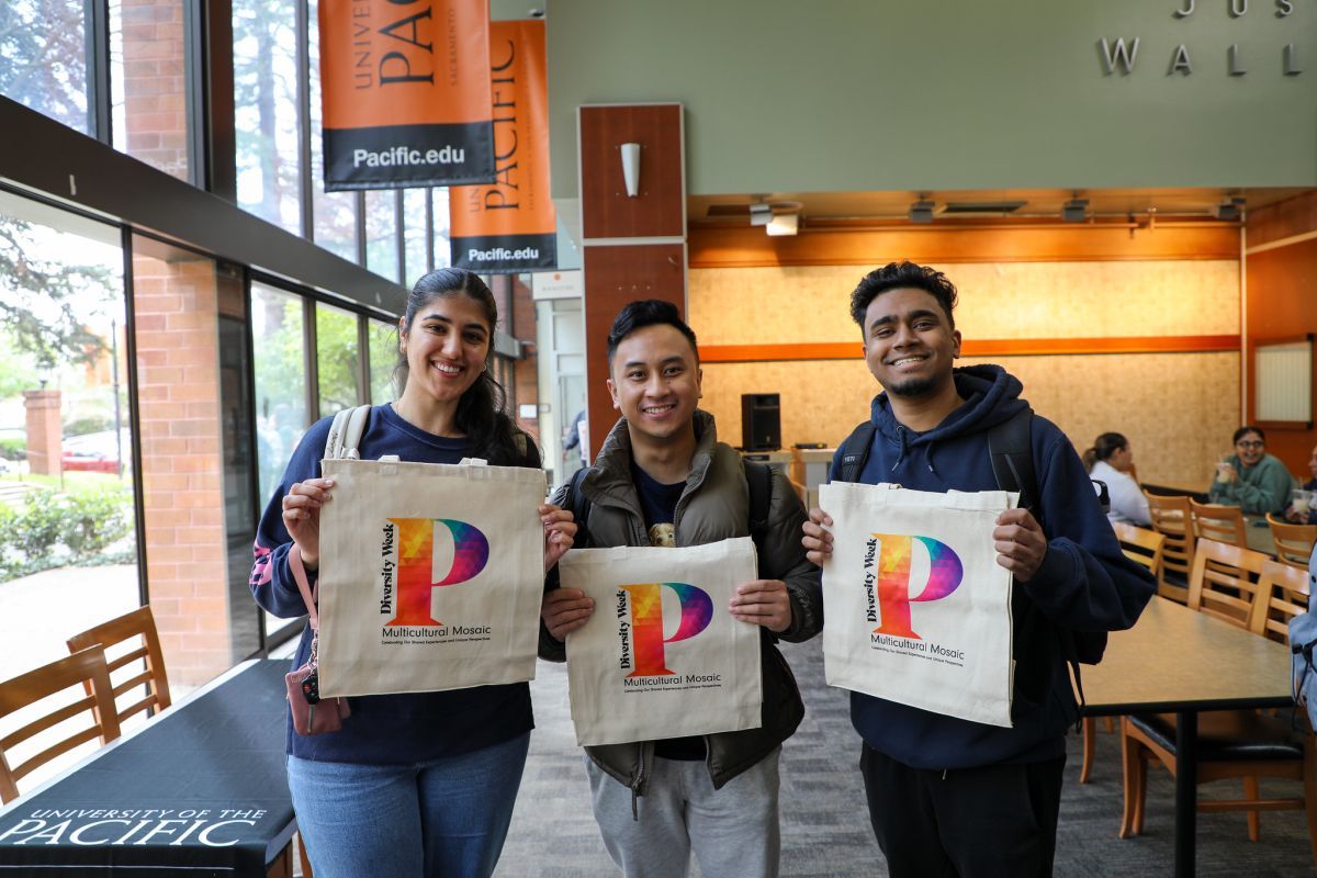 Three students hold tote bags