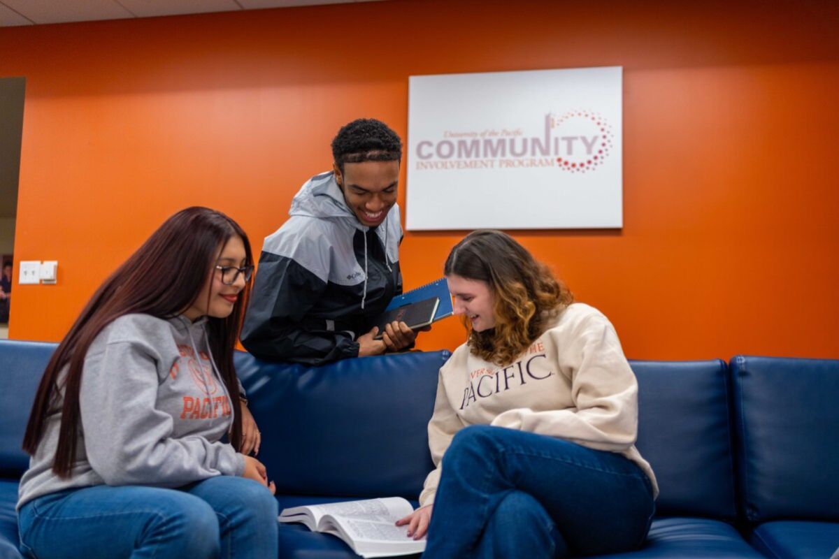 three students gather around a couch