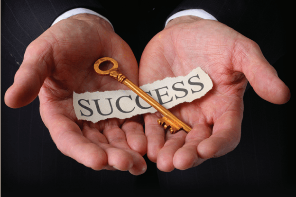 A pair of hands holding a key with the word "success" written on a sheet of paper. 