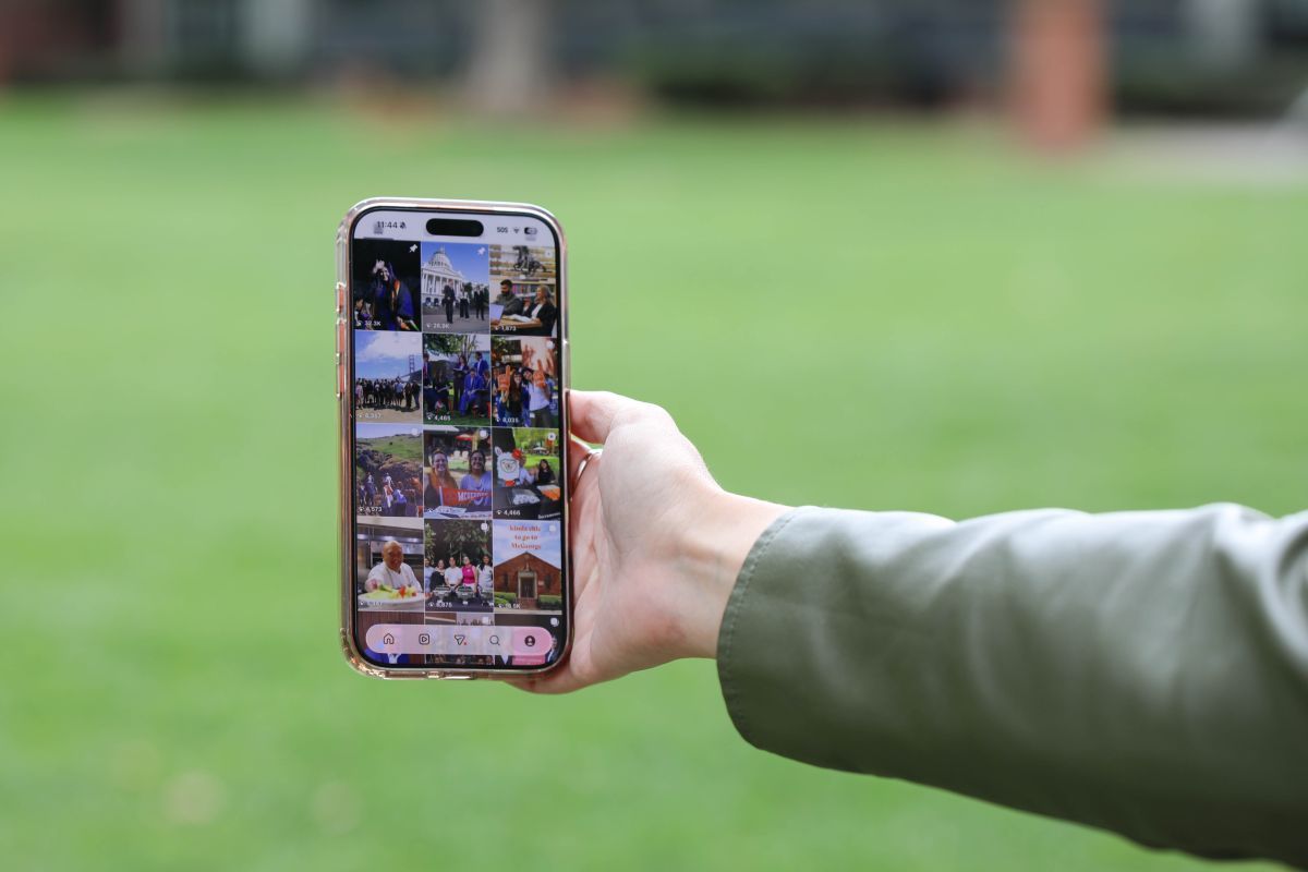 a student holding an iphone, looking at instagram