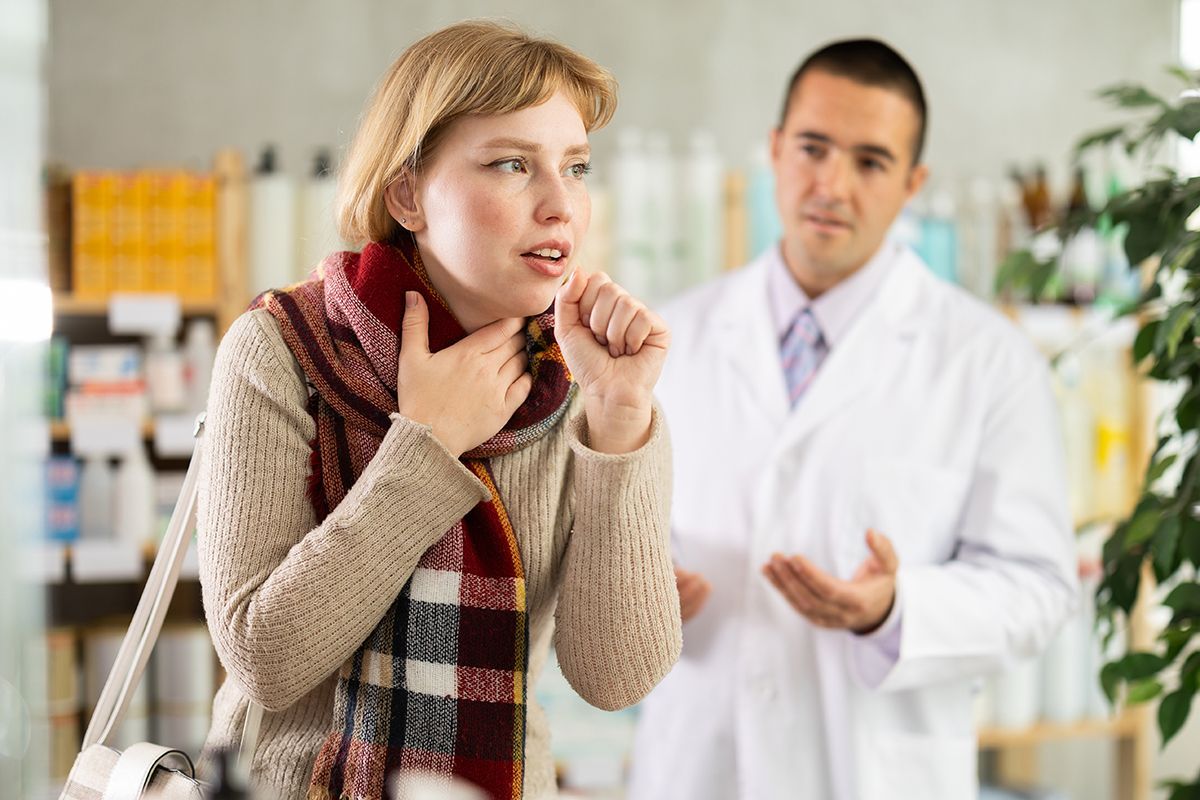 Sick young woman in a pharmacy with a pharmacist