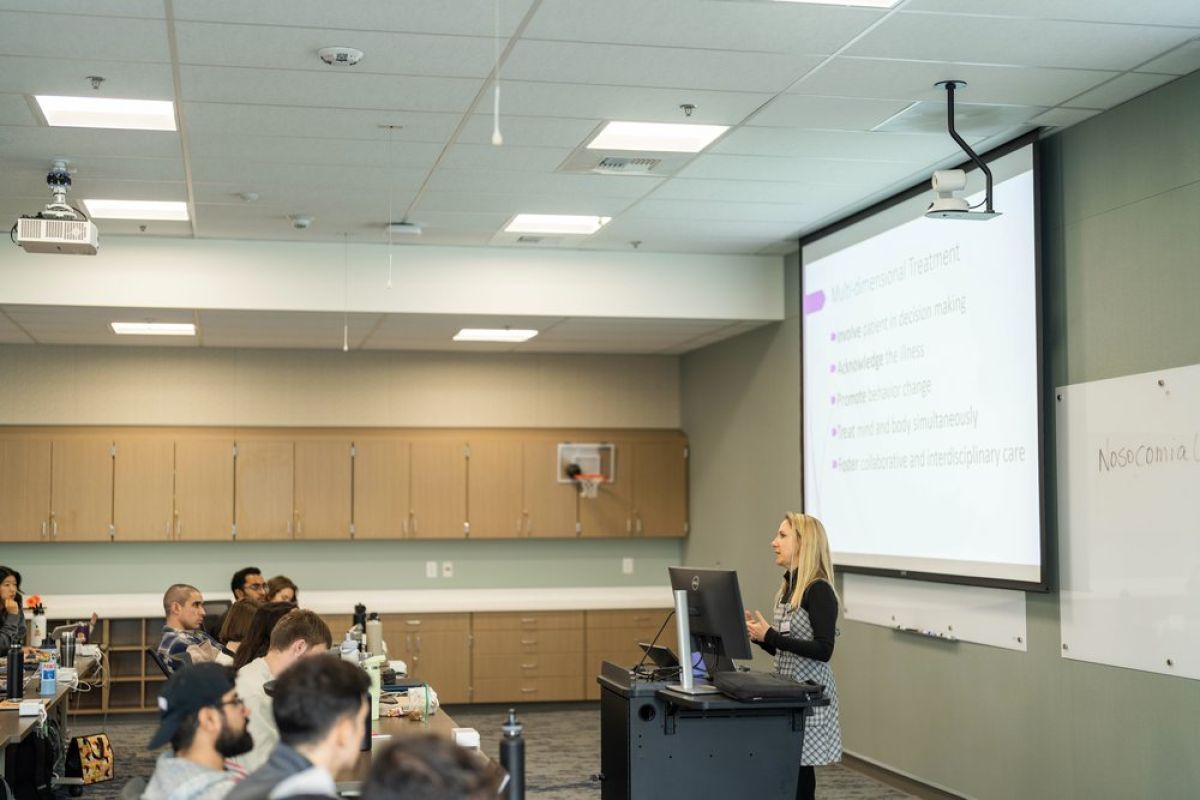 Photo shows a lecturer speaking in front of a class in the CPAE classroom.