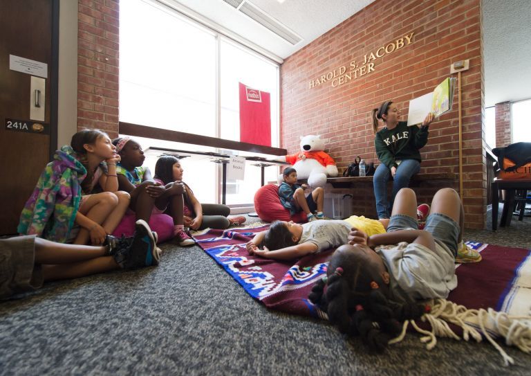 children participating in Pacific Summer Academy listen to a story being read at the Jacoby Center