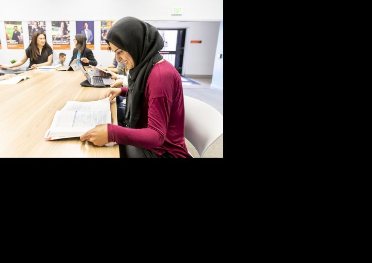 student in classroom looking at textbook