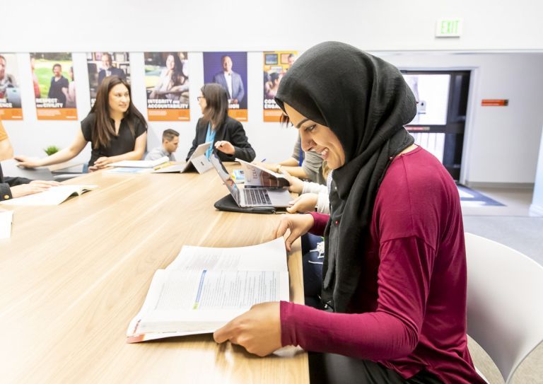 student in classroom looking at textbook