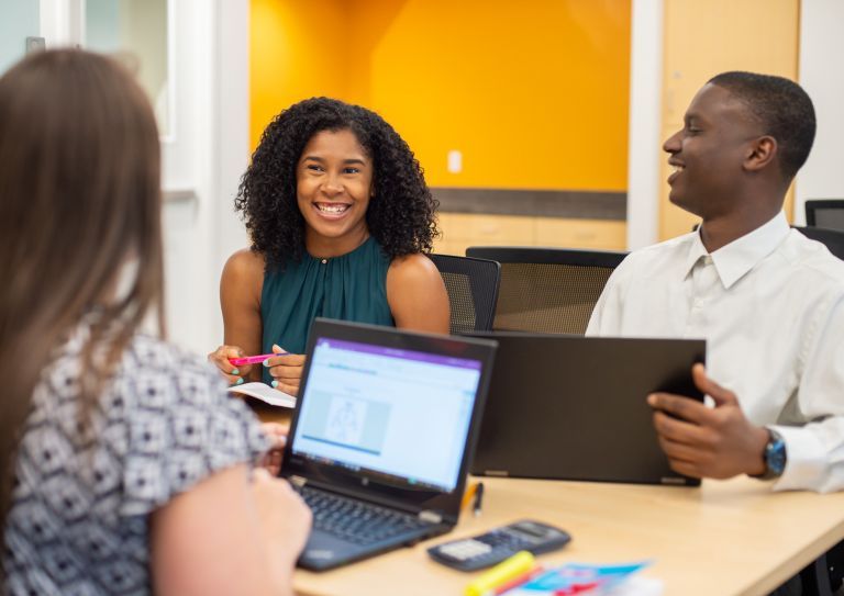 students conversing, on their laptops