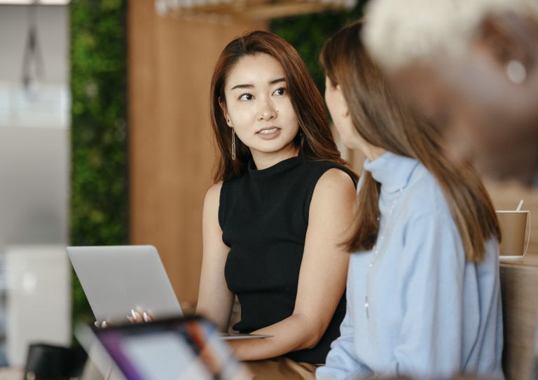 woman using laptop and talking to co-workers