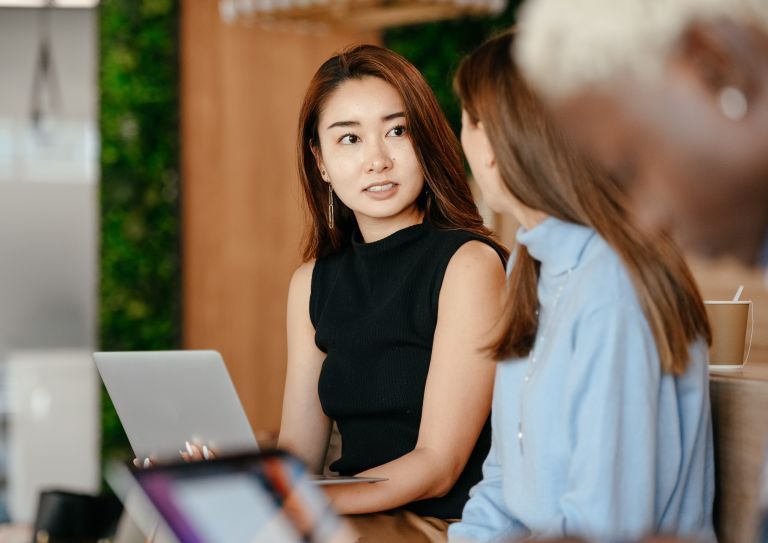woman using laptop and talking to co-workers
