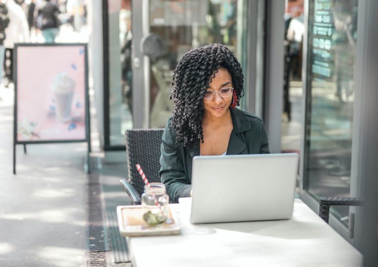 woman using laptop at sidewalk cafe