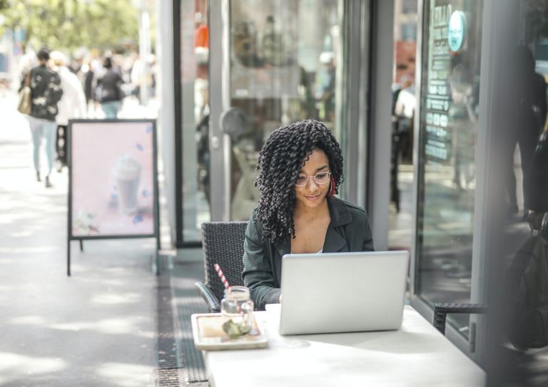 woman using laptop at sidewalk cafe