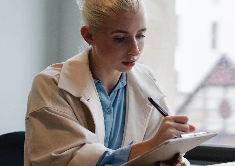 woman writing on clipboard in an office