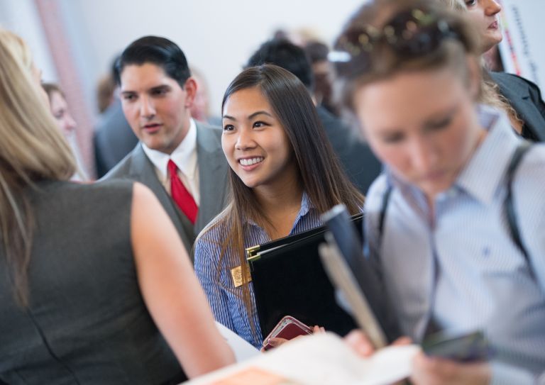 Graduate students meet with potential employers at a career resource center employer fair.