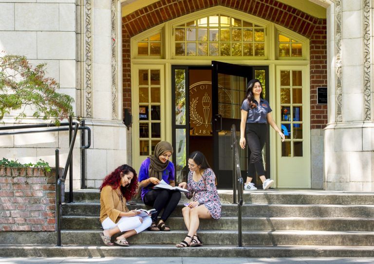 female students sit on the steps of Knoles Hall