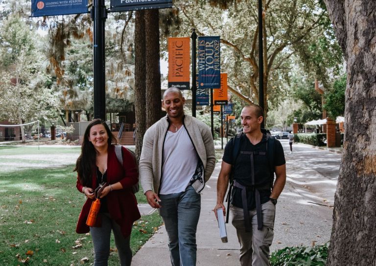 Photo shows three students walking on a sidewalk on Pacific's Sacramento campus. 