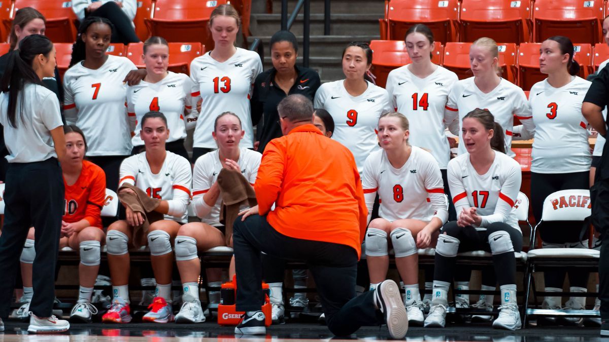 Volleyball team gathers around their coach