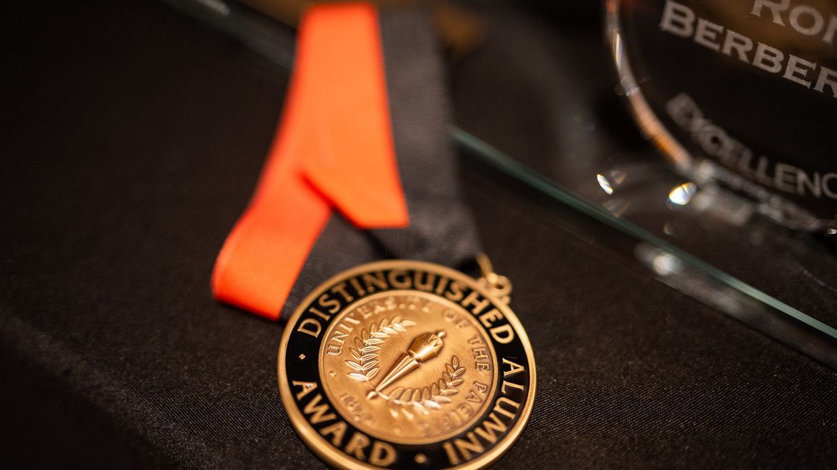 A Distinguished Alumni Award sits on a black table. 
