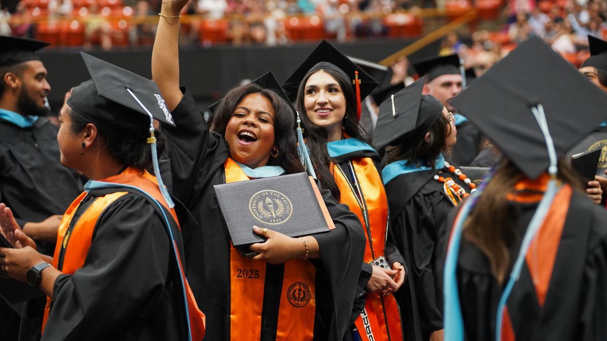 students hold their diplomas at a commencement ceremony