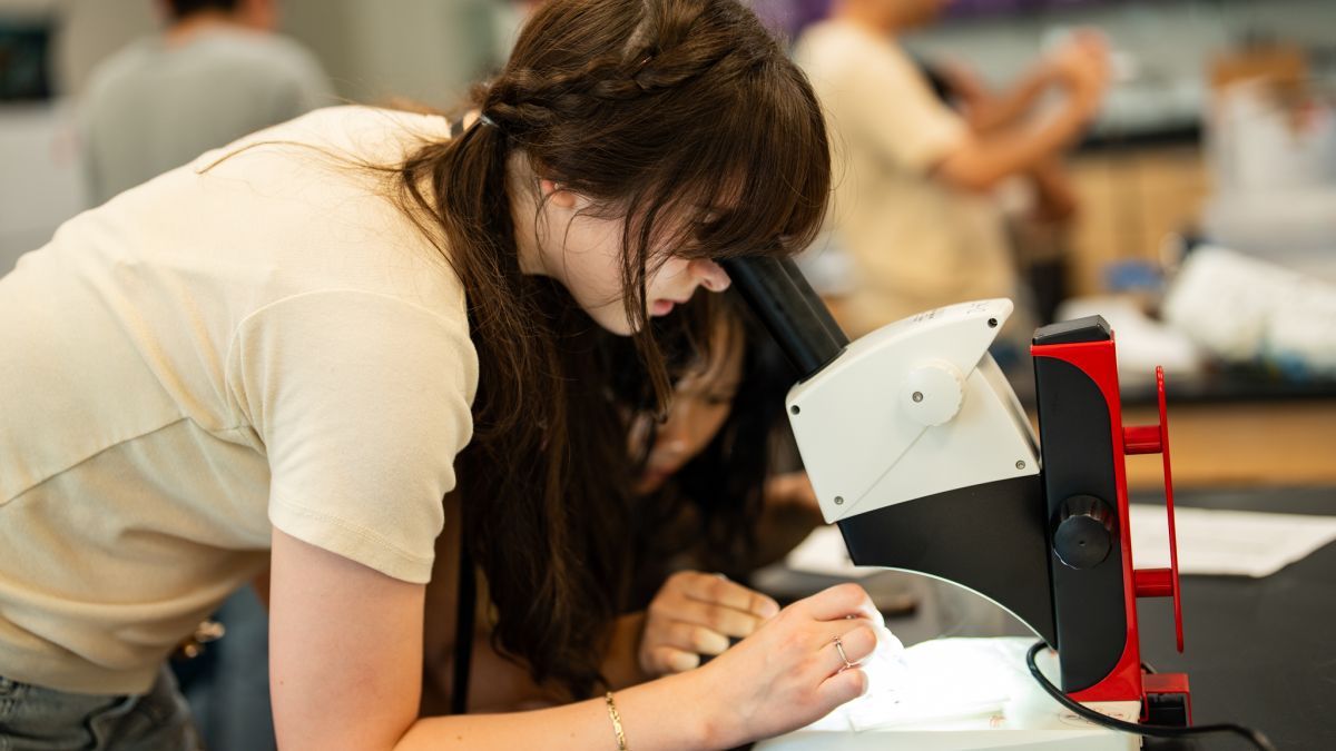 A student looks into a microscope at the Pacific Summer High School Institute.