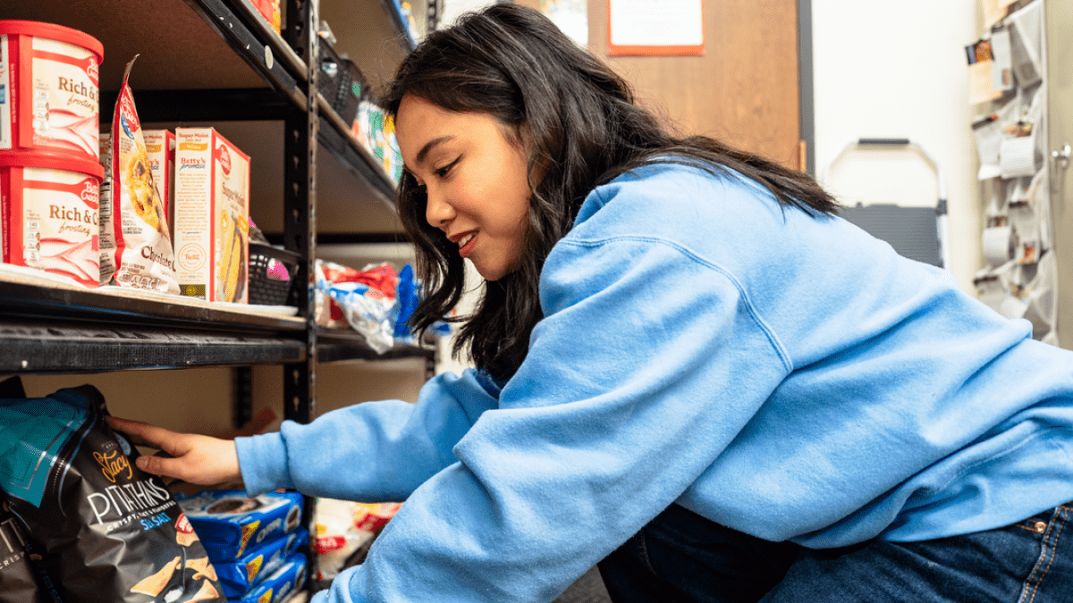 a student restocks shelves at a food pantry