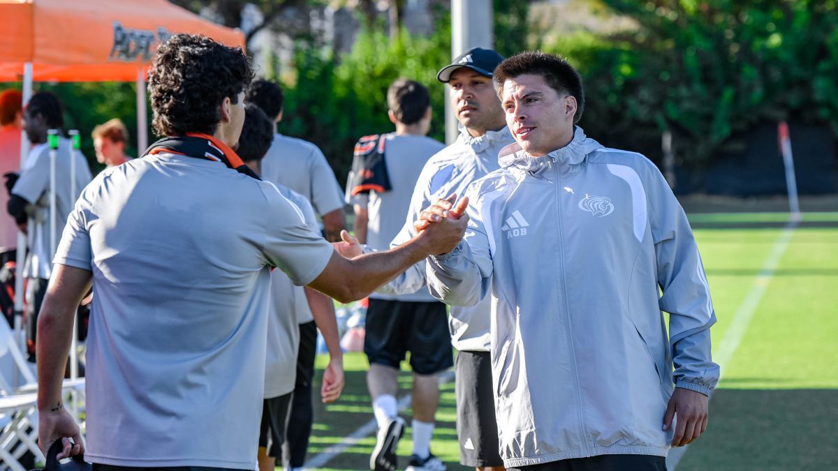 Two men shake hands on a soccer field
