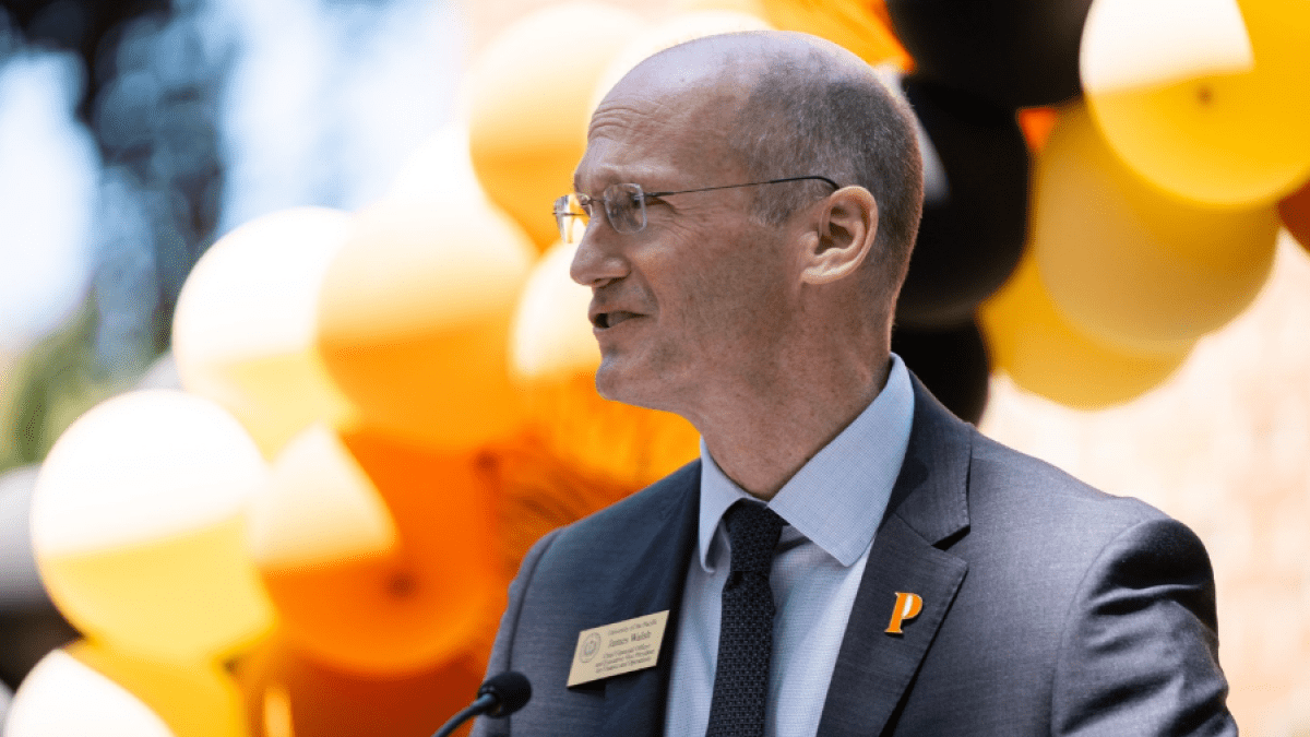 James Walsh stands in front of balloons as he gives a speech