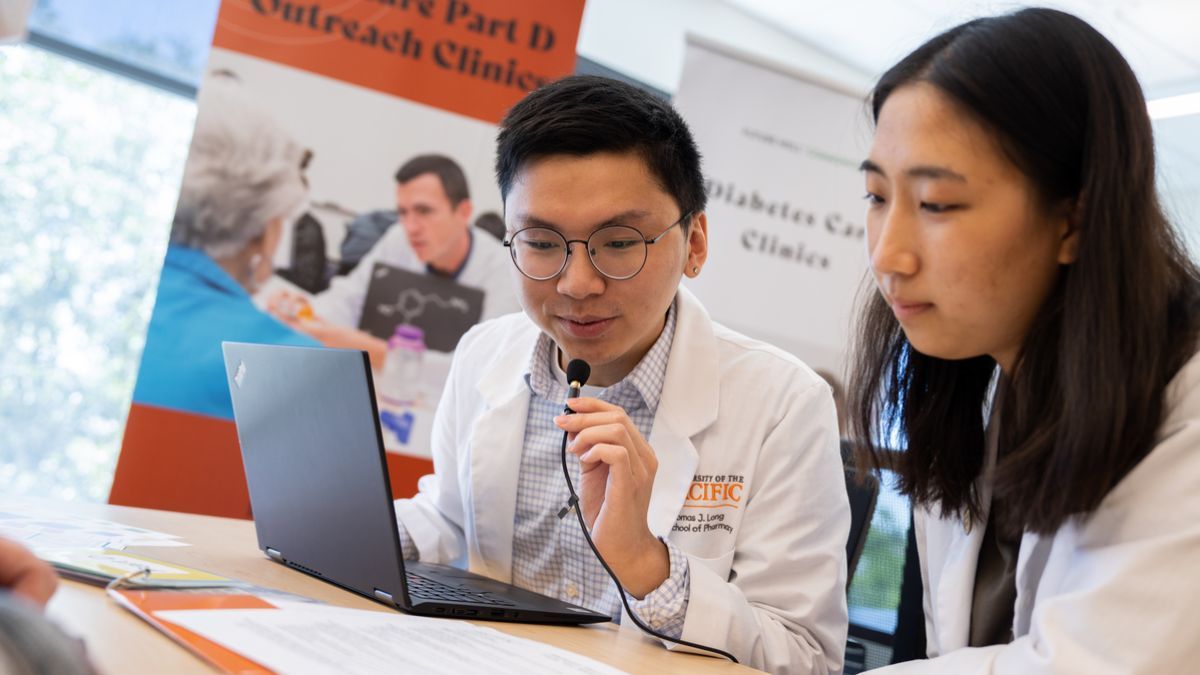Two smiling students in white lab coats 