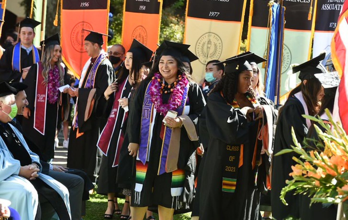 Pacific graduates walking past school and college banners