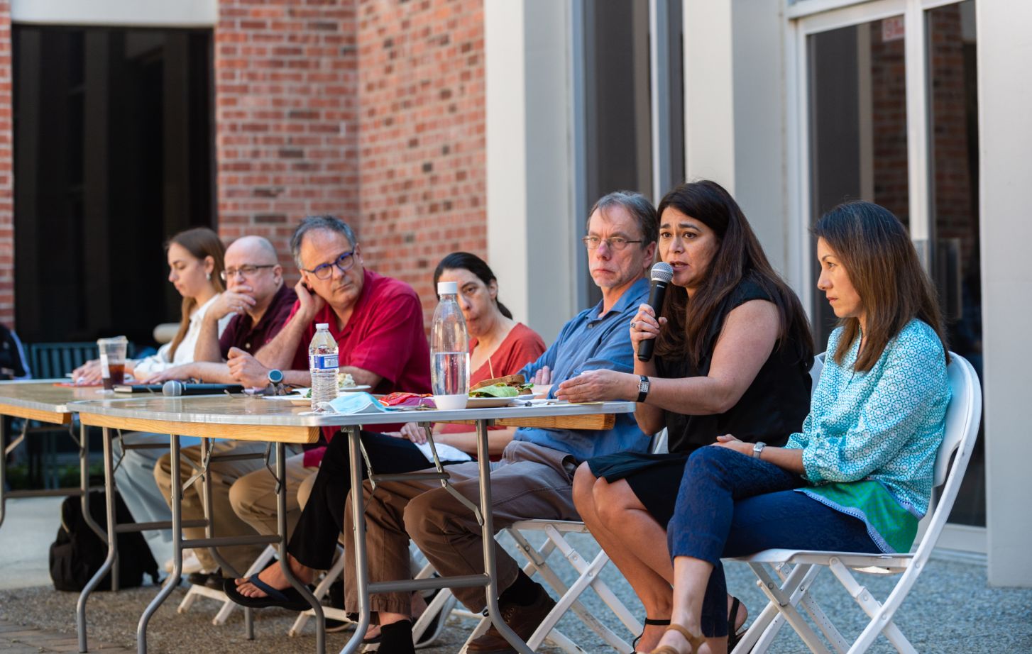 A student and faculty members sit at a long table for a panel discussion.