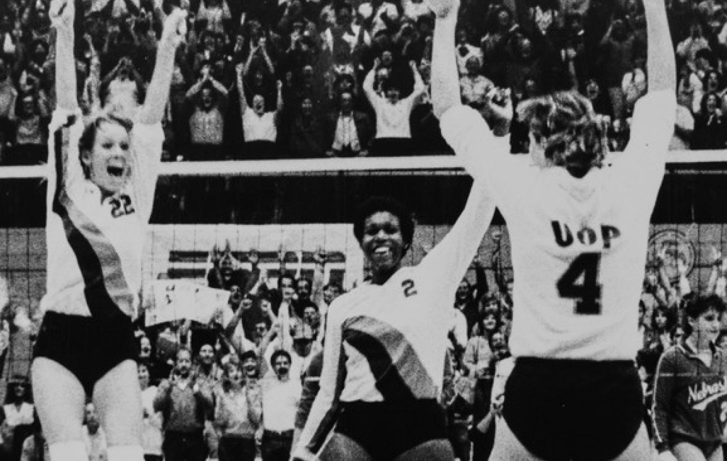 Three Pacific volleyball players celebrate their championship win.