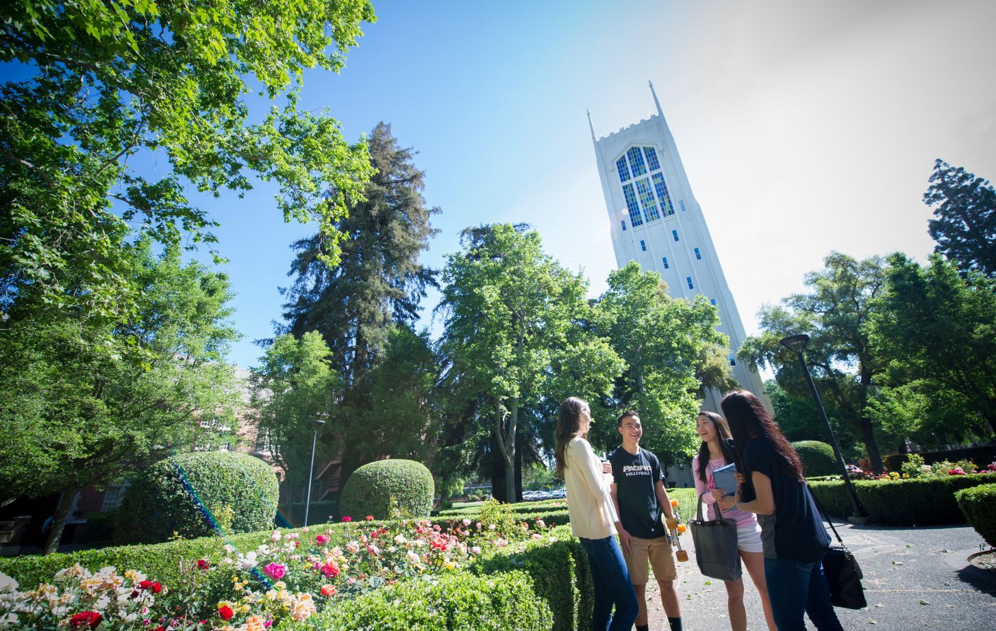 Four students stand in front of Burns Tower