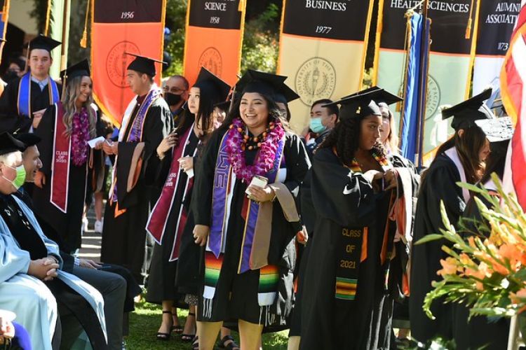 Pacific graduates walking past school and college banners