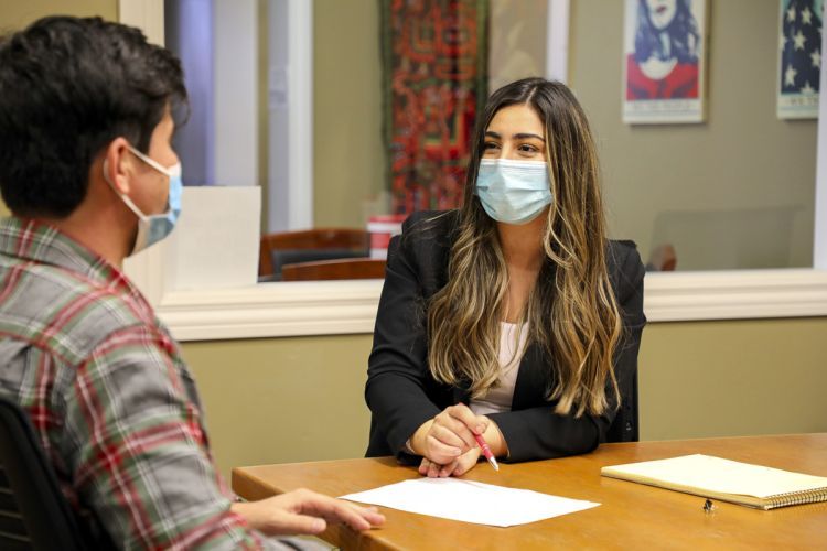 Third-year law student Flora Feizi looks at a client while conducting a meeting in the school's legal clinics. Both individuals are seated.
