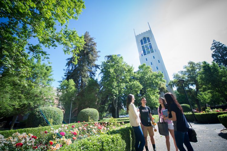Four students stand in front of Burns Tower