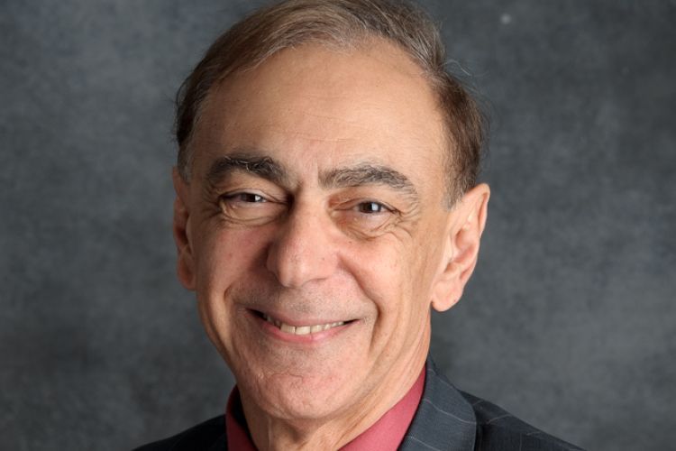 A man in a suit poses for a headshot.