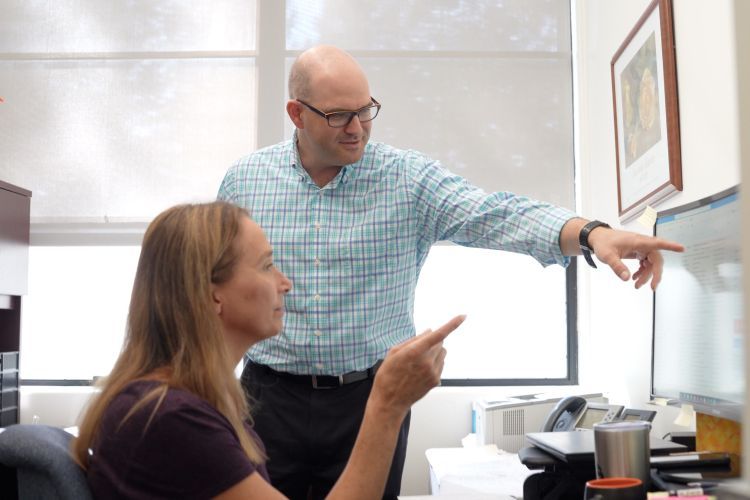 two staff members look at a computer