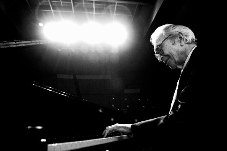 Dave Brubeck is pictured in black and white playing a piano