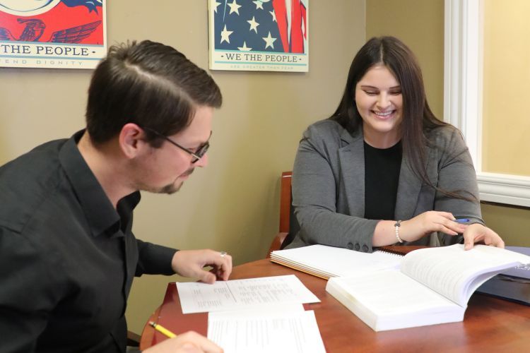 Two students look at books while seated