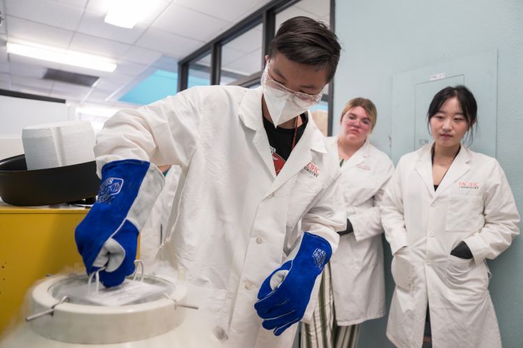 three students wearing white lab coats