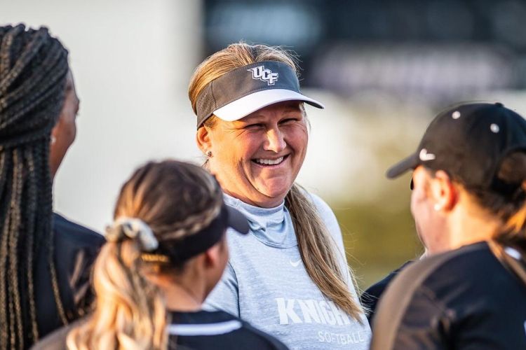 Cindy Ball-Malone smiles as she talks to three softball players