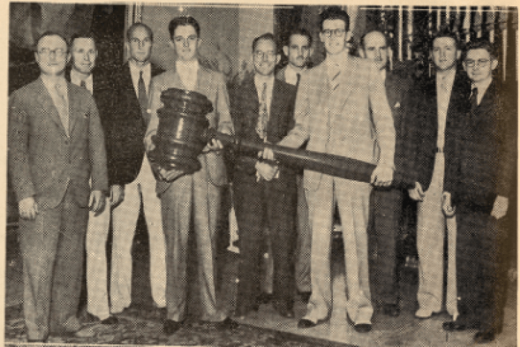 A group of alumni board officers hold a 5-foot gavel