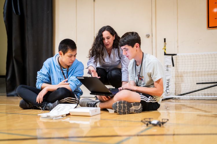 students practice using a drone with the help of a faculty member