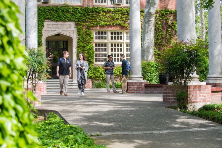 students stand by columns on campus