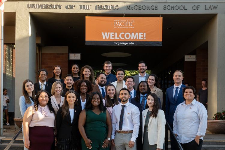 A group of 23 students pose on the steps of a staircase outdoors