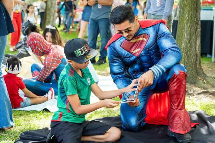A student with the Community Involvement Program reads to children in Stockton during the annual Family Day at the Park.
